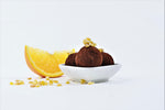 Orange truffles in a bowl with orange slice on a side