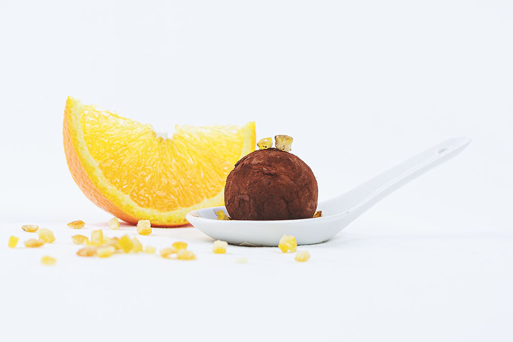 Orange truffle in a spoon with orange slice on a side
