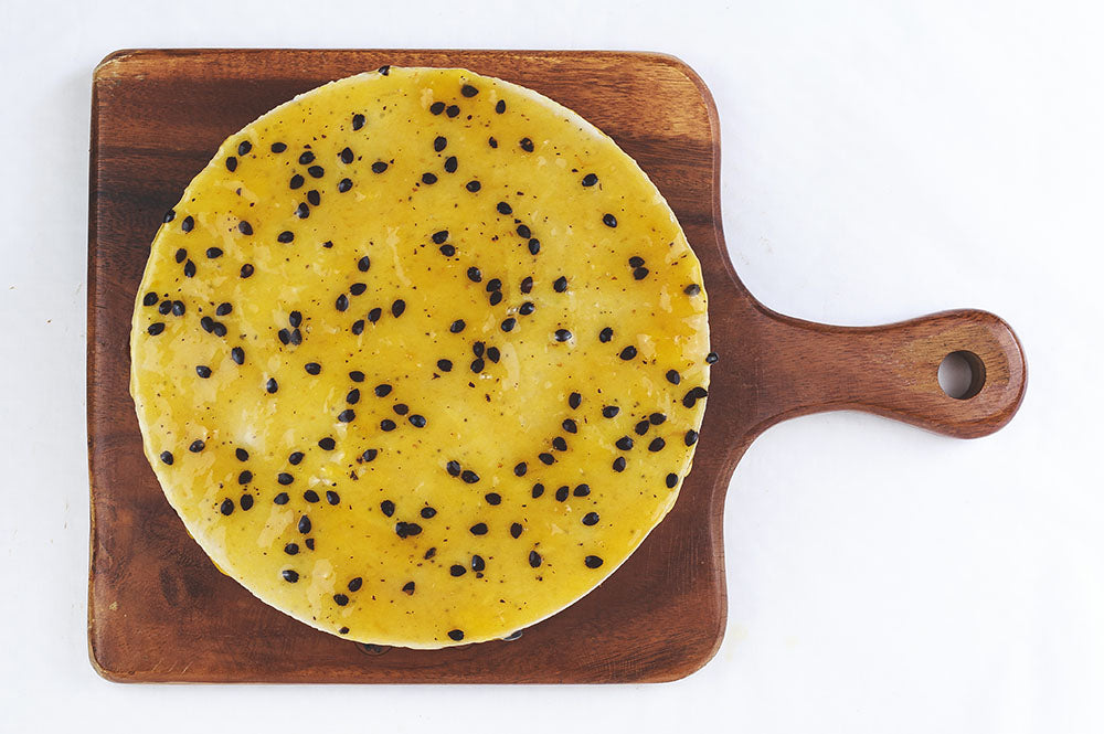 
            
                Load image into Gallery viewer, Top view of Passionfruit cheesecake on a wooden board
            
        