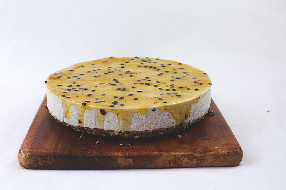 
            
                Load image into Gallery viewer, Side view of Passionfruit cheesecake on a wooden board
            
        