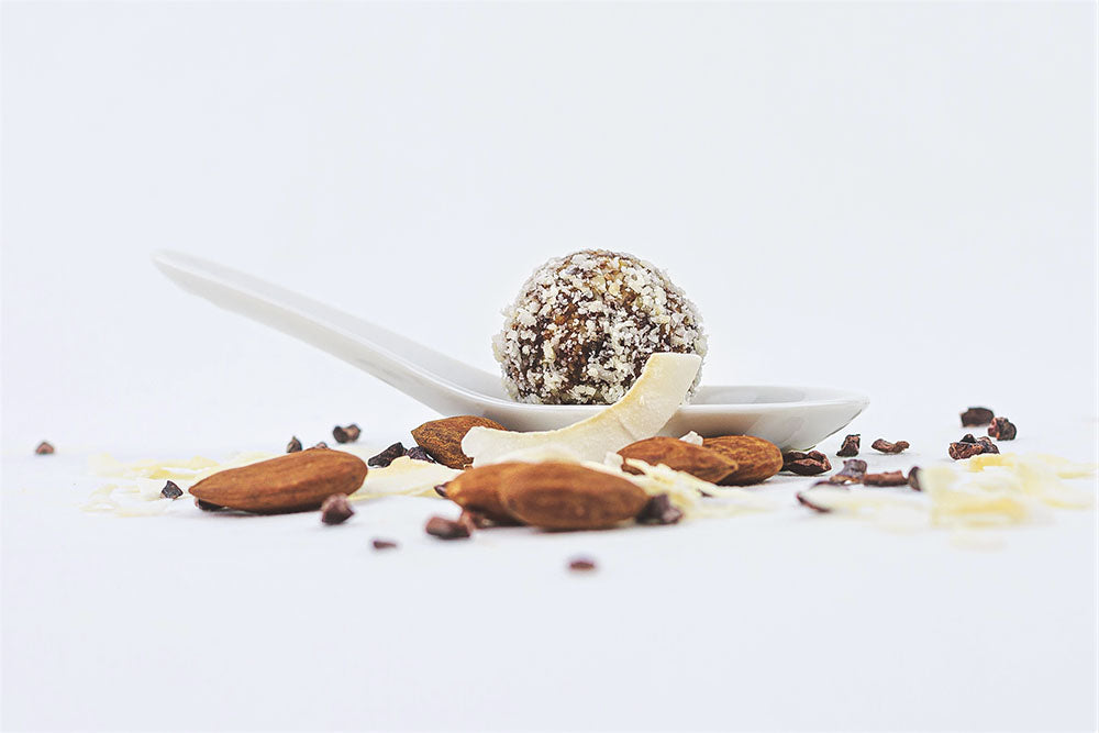 Raw truffles in a bowl with Almonds, shredded chocolates and dry coconut all-around