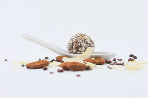 Raw truffles in a bowl with Almonds, shredded chocolates and dry coconut all-around