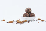 3 Chocolate Raw Truffles in a while bowl with lots of almonds and chocolate shreds all-around