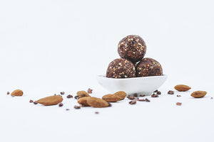 
            
                Load image into Gallery viewer, 3 Chocolate Raw Truffles in a while bowl with lots of almonds and chocolate shreds all-around
            
        